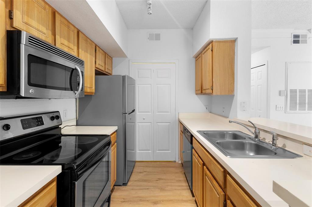 A kitchen features light wood cabinets, stainless steel appliances, and a double-basin sink — 13037 MULBERRY PARK DRIVE UNIT 529, ORLANDO, FL