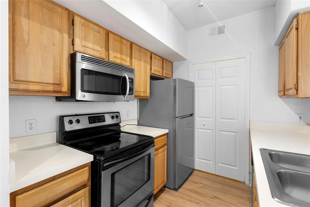 A kitchen features wood cabinets, stainless steel appliances, and white countertops — 13037 MULBERRY PARK DRIVE UNIT 529, ORLANDO, FL