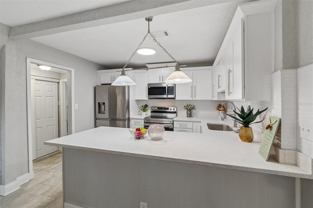 A kitchen features white cabinets, stainless steel appliances, and a white quartz breakfast bar — 804 VALENCIA ROAD, PLANT CITY, FL