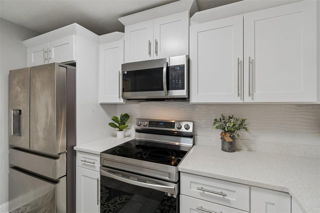 A kitchen features white cabinets, stainless steel appliances, and light-colored quartz countertops — 804 VALENCIA ROAD, PLANT CITY, FL