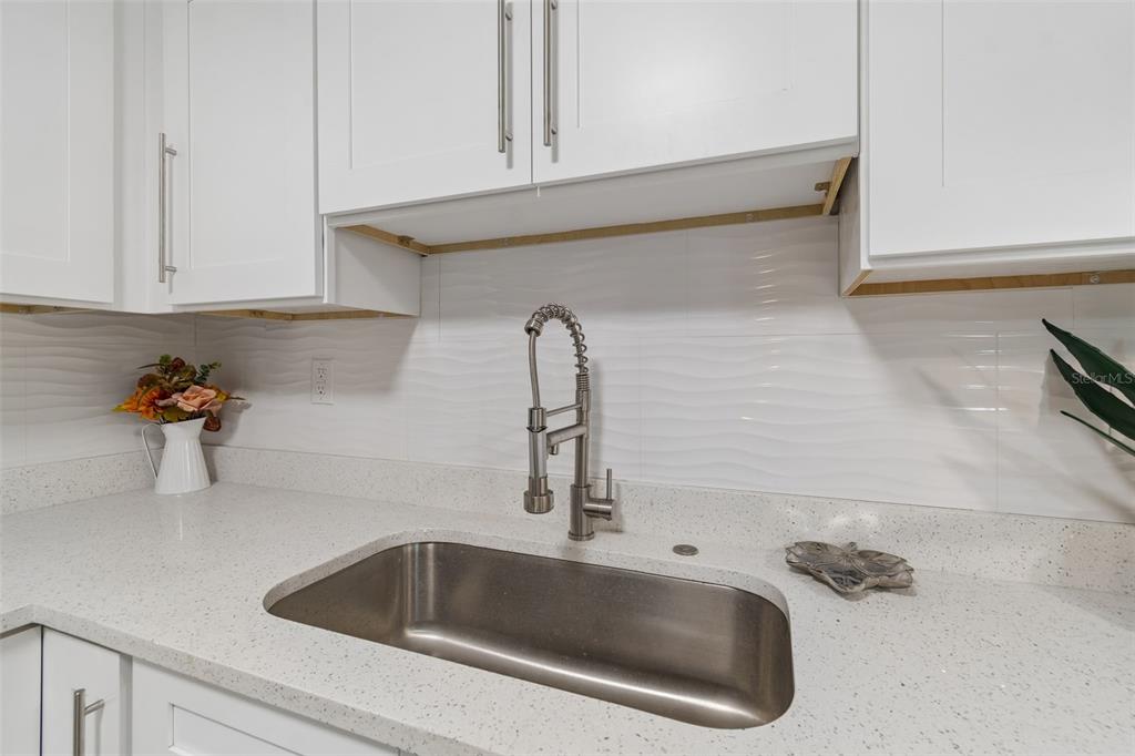 A kitchen sink with a gooseneck faucet sits below white cabinets and a tiled backsplash — 804 VALENCIA ROAD, PLANT CITY, FL