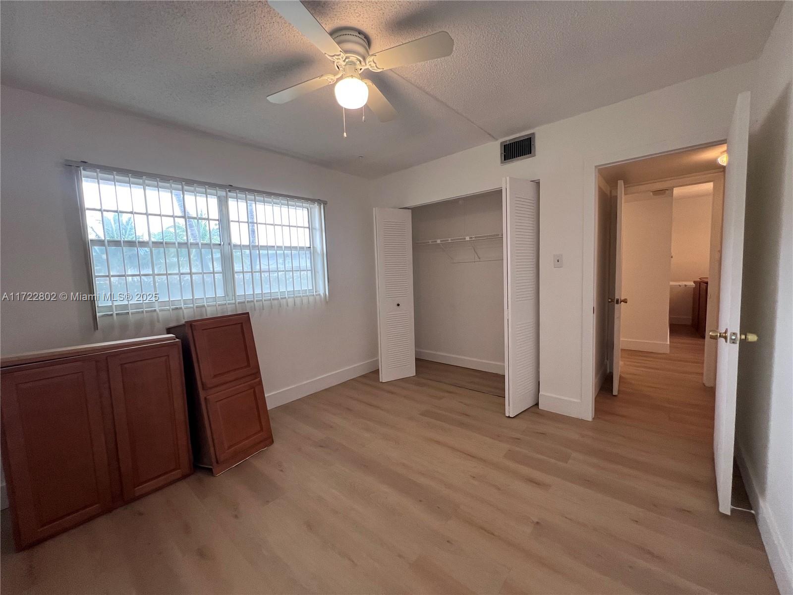 A bedroom features light wood-look flooring, a ceiling fan, a closet, and two wooden cabinets — 7400 NW 4th Pl # 106, Margate FL 33063, MARGATE, FL