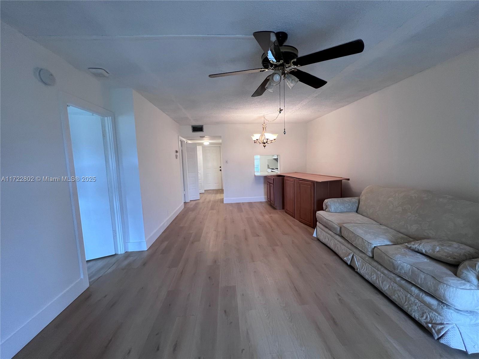 A living room features light wood-look flooring, a ceiling fan, and a built-in wooden counter — 7400 NW 4th Pl # 106, Margate FL 33063, MARGATE, FL