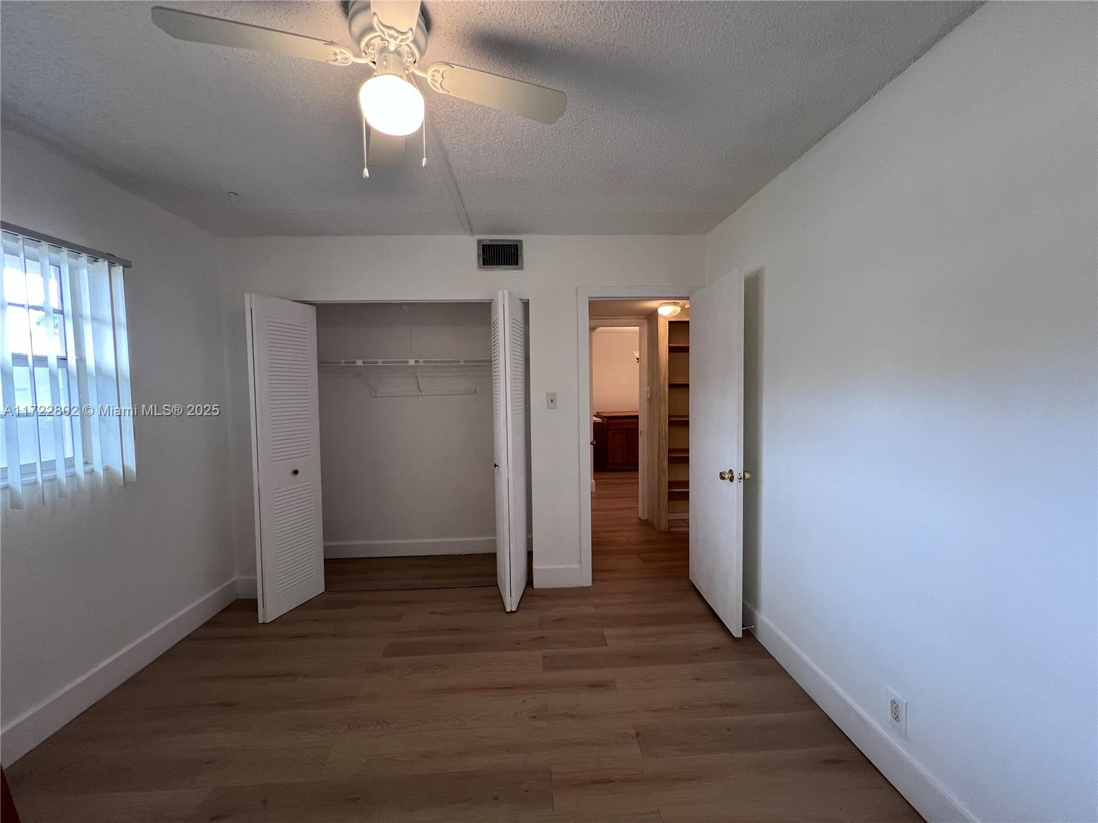 A bedroom with white walls, wood-look flooring, a ceiling fan, and an open closet — 7400 NW 4th Pl # 106, Margate FL 33063, MARGATE, FL