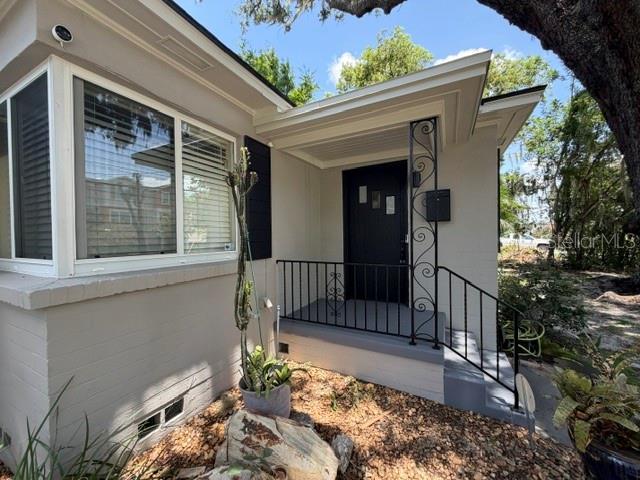 The exterior of a house features a front porch with a black door and metal railing — 1009 E MARKS STREET, ORLANDO, FL