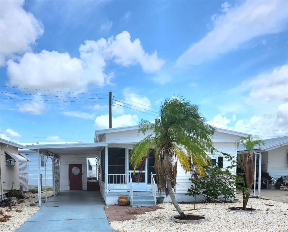 A white mobile home with a carport, a screened-in porch, and a palm tree — 1715 ILLINOIS AVENUE, BRADENTON, FL