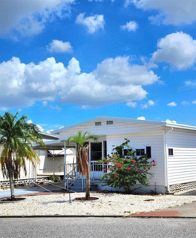 A white mobile home with a palm tree and a flowering bush in the front yard — 1715 ILLINOIS AVENUE, BRADENTON, FL