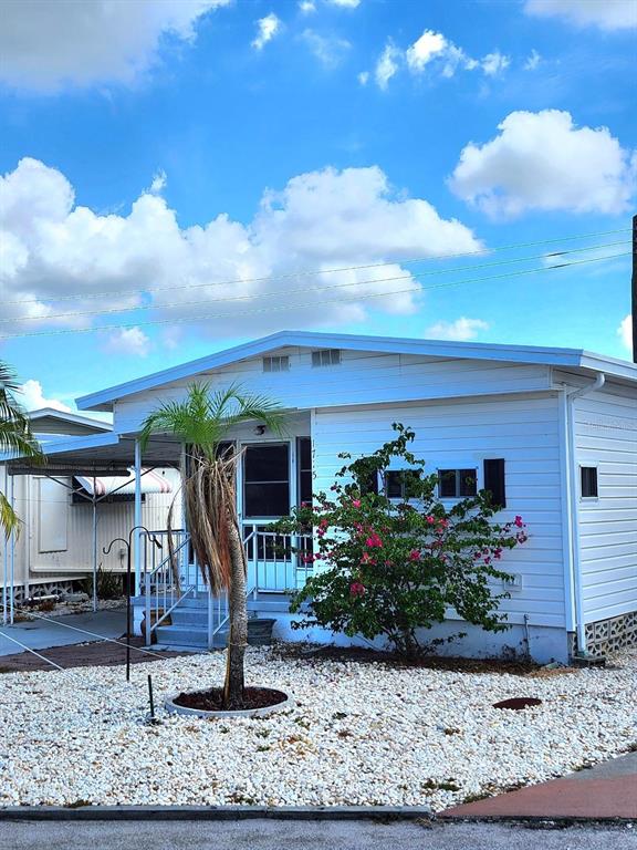 A white mobile home features a palm tree and a flowering bush in the front yard — 1715 ILLINOIS AVENUE, BRADENTON, FL