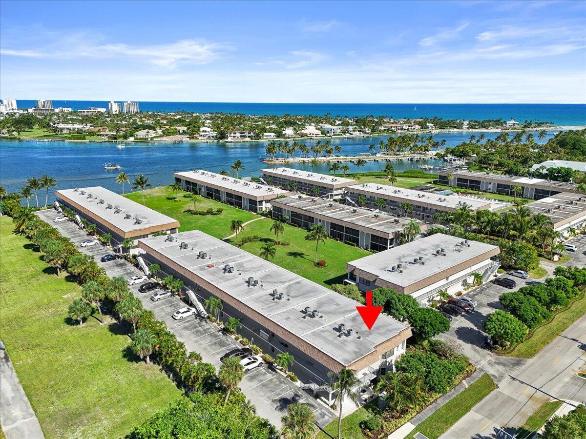 An aerial view shows a multi-story apartment complex with a red arrow pointing to a roof — 755 Saturn Street # H101, Jupiter FL 33477, JUPITER, FL