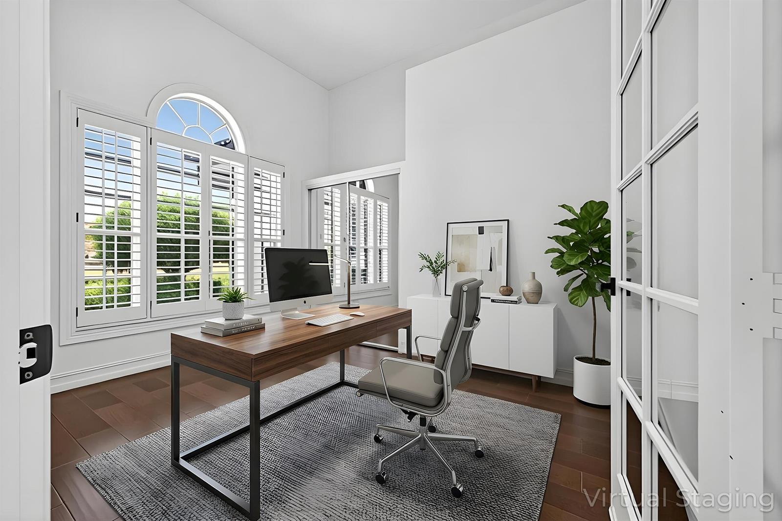 A home office with a wooden desk, gray chair, area rug, and large arched window — 14780 Horseshoe Trace, Wellington FL 33414, WELLINGTON, FL