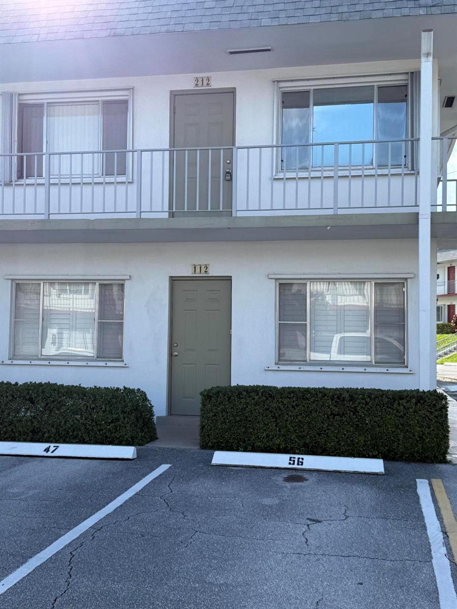 A two-story apartment building exterior features two stacked units with numbered doors and parking spaces — 3160 Lake Osborne Drive # 112, FL 33461, FL