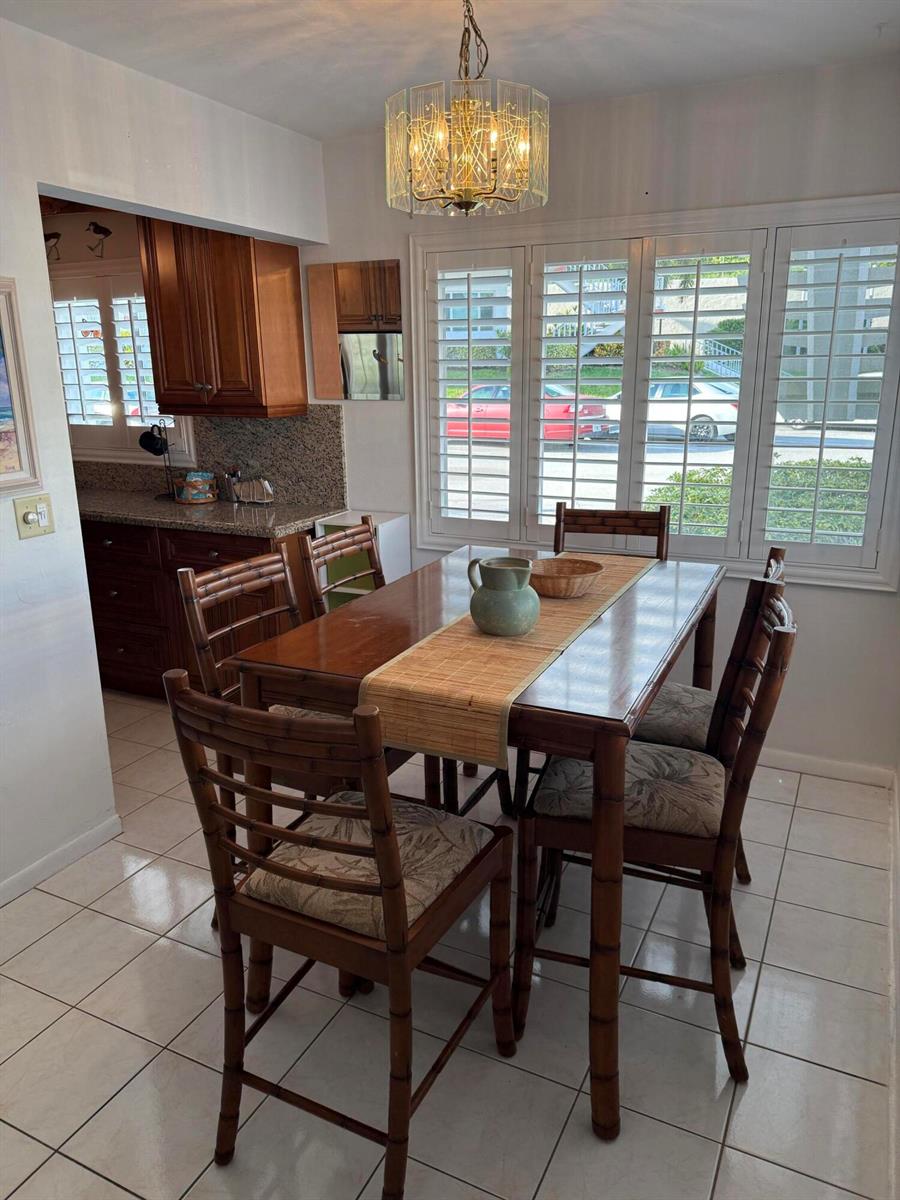 A dining area features a wooden table with bamboo chairs, tile flooring, and plantation shutters — 3160 Lake Osborne Drive # 112, FL 33461, FL