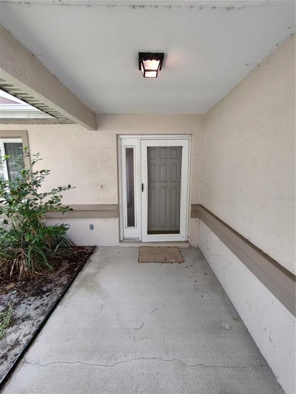 A concrete porch leads to a white front door with a side light and lantern — 6202 SW 100TH LOOP, OCALA, FL
