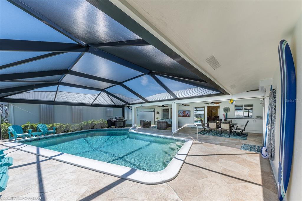 A screened-in patio features a swimming pool, stone decking, and outdoor dining furniture — 2060 VIA SEVILLE, PUNTA GORDA, FL