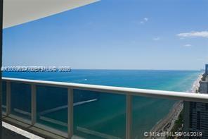 A high-rise balcony overlooks the ocean and a sandy beach under a clear blue sky — 1830 S OCEAN DR # 3910, Hallandale Beach FL 33009, HALLANDALE BEACH, FL