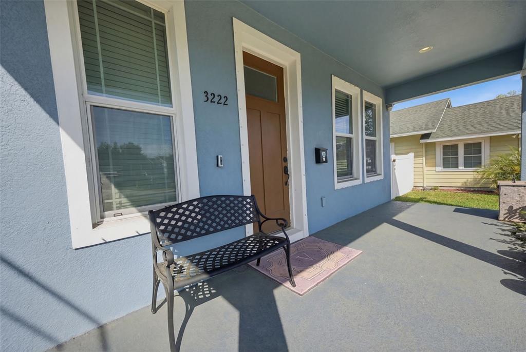 A blue house exterior features a covered front porch with a black metal bench — 3222 PRESCOTT STREET N, ST PETERSBURG, FL