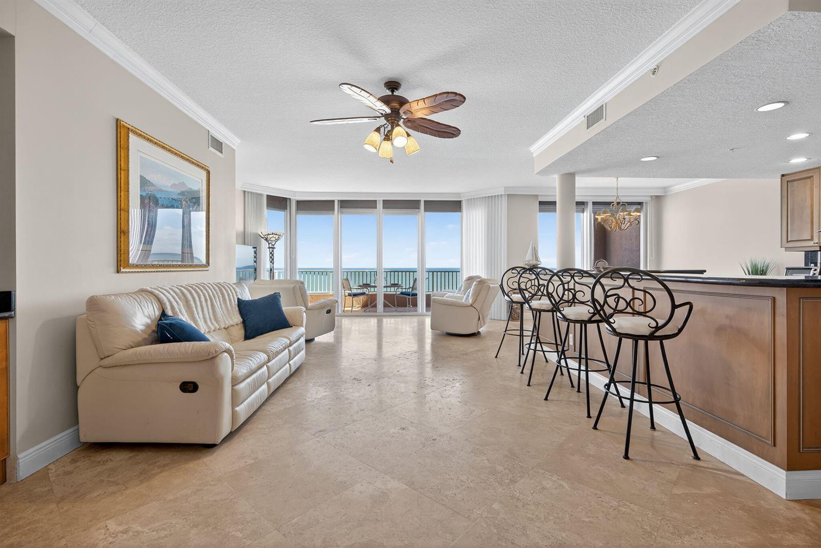 A living room with tile floors, a white sofa, and a bar overlooking the ocean — 700 Ocean Royale Way # 3, Juno Beach FL 33408, JUNO BEACH, FL
