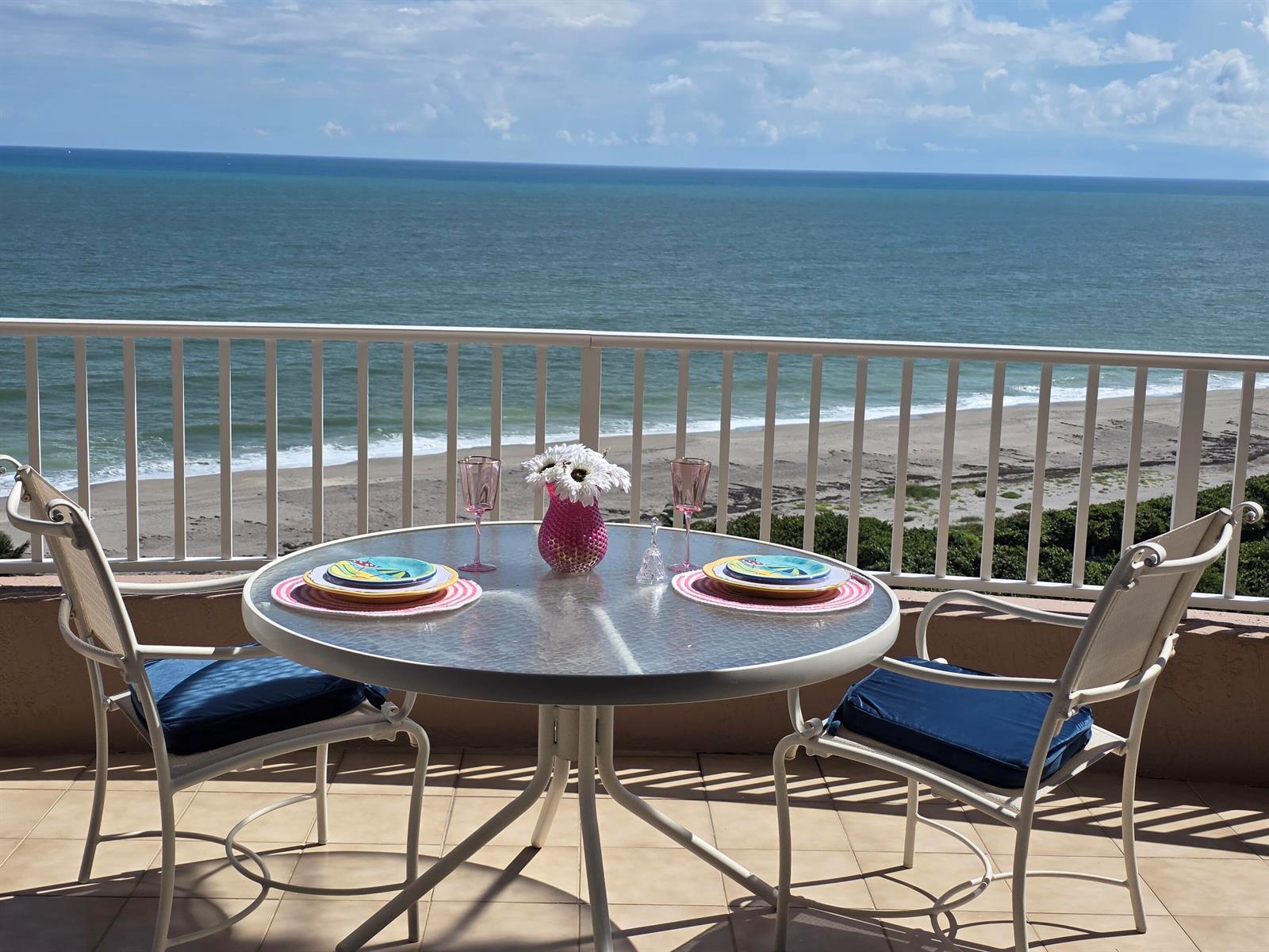A balcony with a round glass table, two chairs, and a view of the ocean — 700 Ocean Royale Way # 3, Juno Beach FL 33408, JUNO BEACH, FL