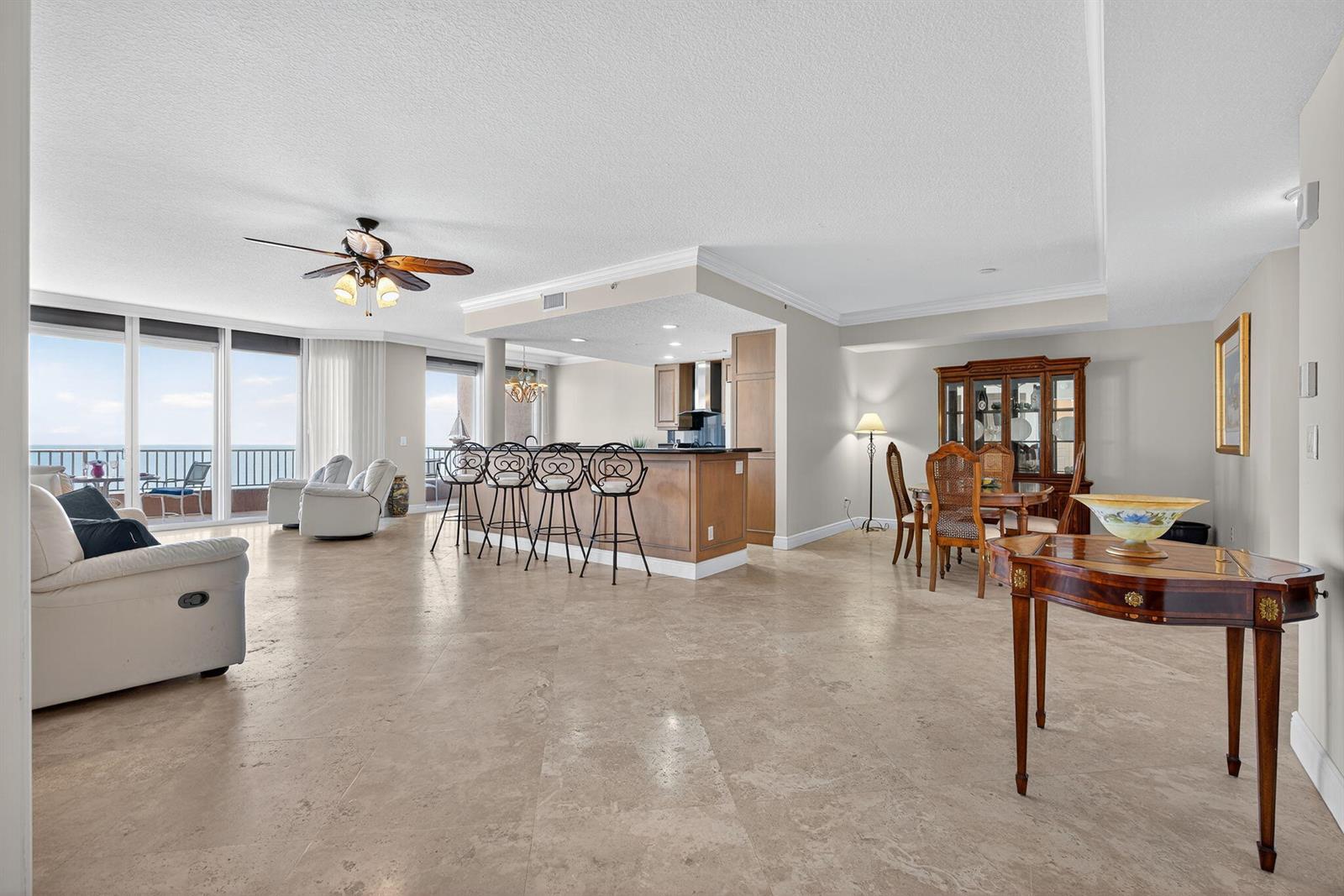 An open-concept living and dining area features tile flooring, a kitchen island, and ocean views — 700 Ocean Royale Way # 3, Juno Beach FL 33408, JUNO BEACH, FL