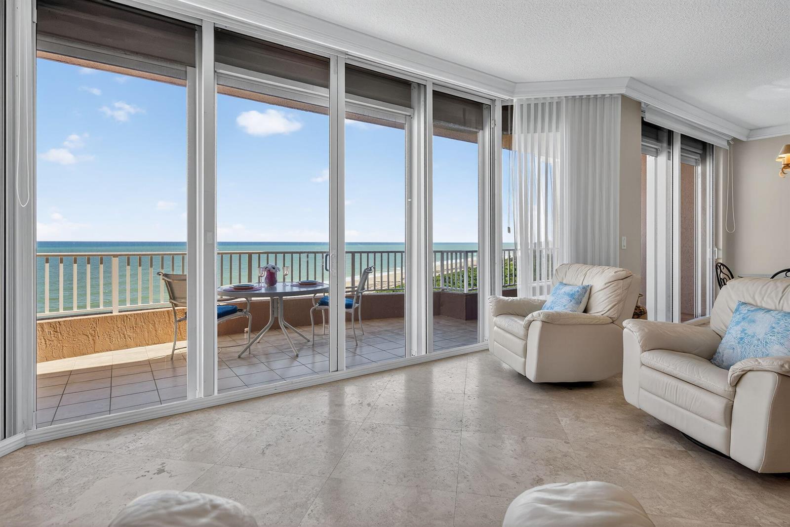 A living room with tile floors and large sliding glass doors opening to an oceanfront balcony — 700 Ocean Royale Way # 3, Juno Beach FL 33408, JUNO BEACH, FL