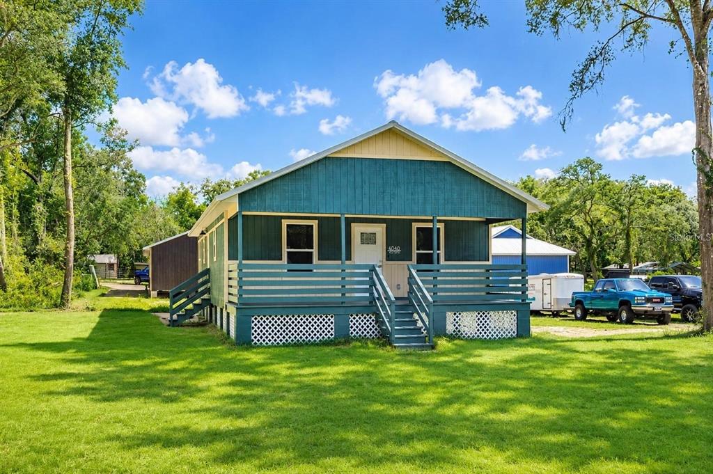 A teal-sided house with a front porch and lattice skirting sits on a grassy lot — 4839 CR 686, WEBSTER, FL