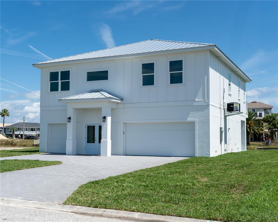 A two-story white house with a metal roof and a paved driveway under a blue sky — 4050 JEWFISH DRIVE, HUDSON, FL