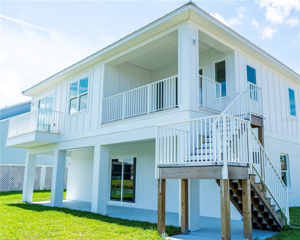 A white two-story house with an elevated deck, outdoor staircase, and a covered ground-level patio — 4050 JEWFISH DRIVE, HUDSON, FL
