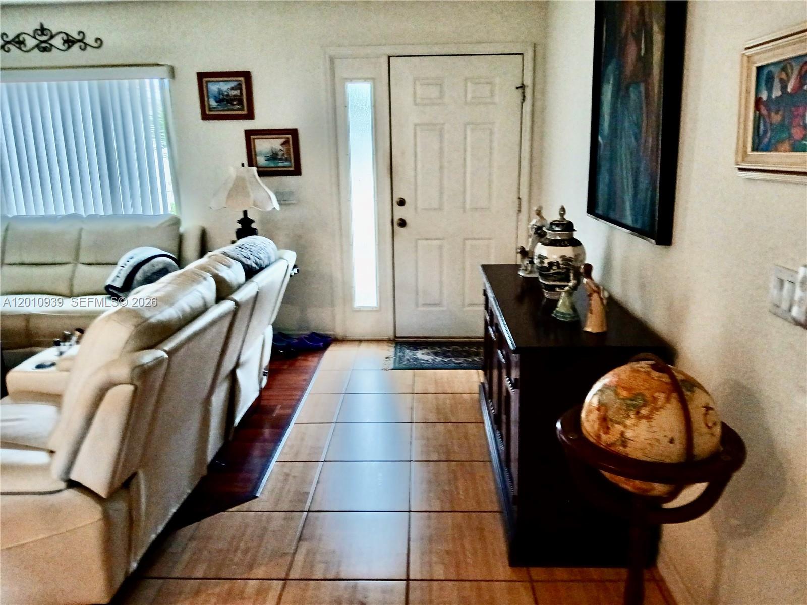 An entryway features tile flooring, a dark wood console table, a globe, and a front door — 5880 SW 102, Ocala FL 34476, OCALA, FL