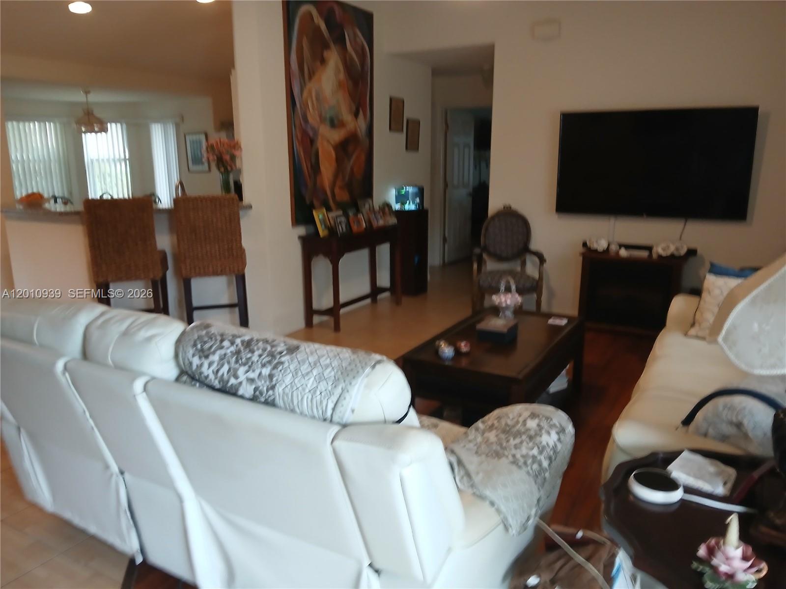A living room features white leather sofas, a dark wood coffee table, and a television — 5880 SW 102, Ocala FL 34476, OCALA, FL