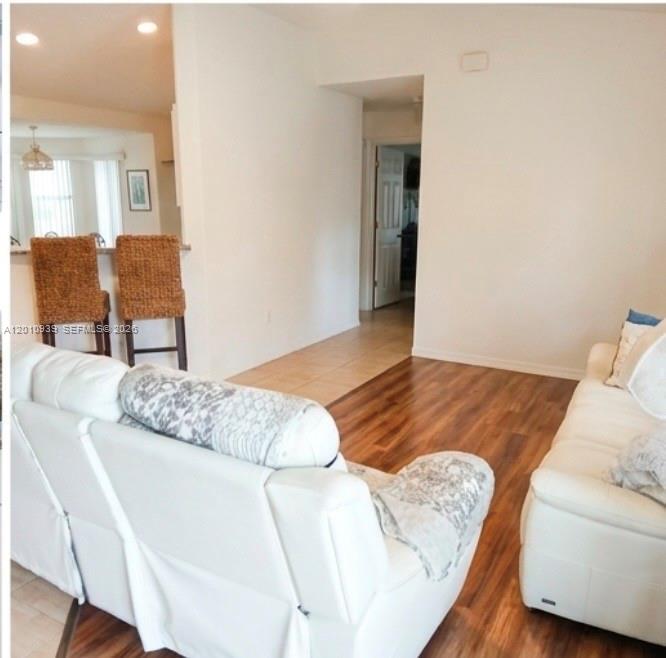A living room features white leather sofas, wood-look flooring, and a breakfast bar with stools — 5880 SW 102, Ocala FL 34476, OCALA, FL