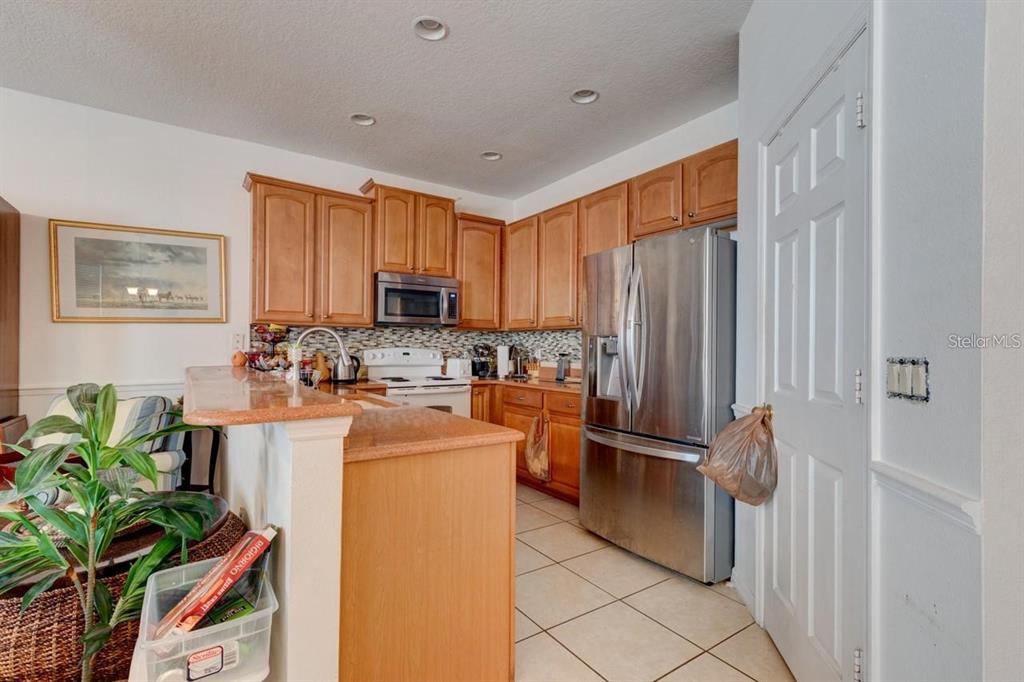 A kitchen features wood cabinets, stainless steel appliances, a breakfast bar, and tile flooring — 1128 TRAVERTINE TERRACE, SANFORD, FL