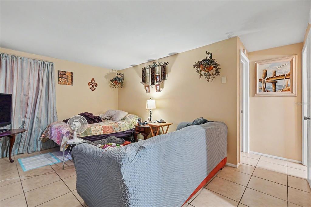 A living room with tile flooring, a bed, a gray sofa, and beige walls — 5513 OCEANIC ROAD, HOLIDAY, FL
