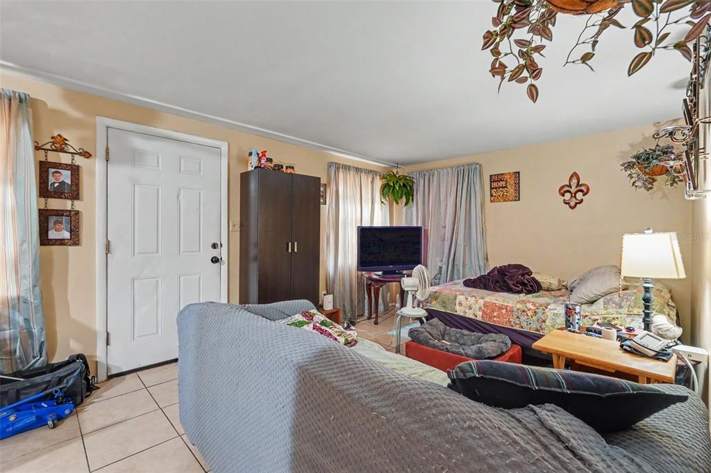 A living room features tiled floors, a sofa, a bed, a television, and a door — 5513 OCEANIC ROAD, HOLIDAY, FL