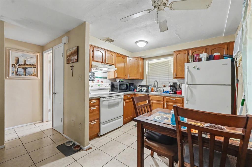 A kitchen with wood cabinets, white appliances, tile flooring, and a small dining table — 5513 OCEANIC ROAD, HOLIDAY, FL