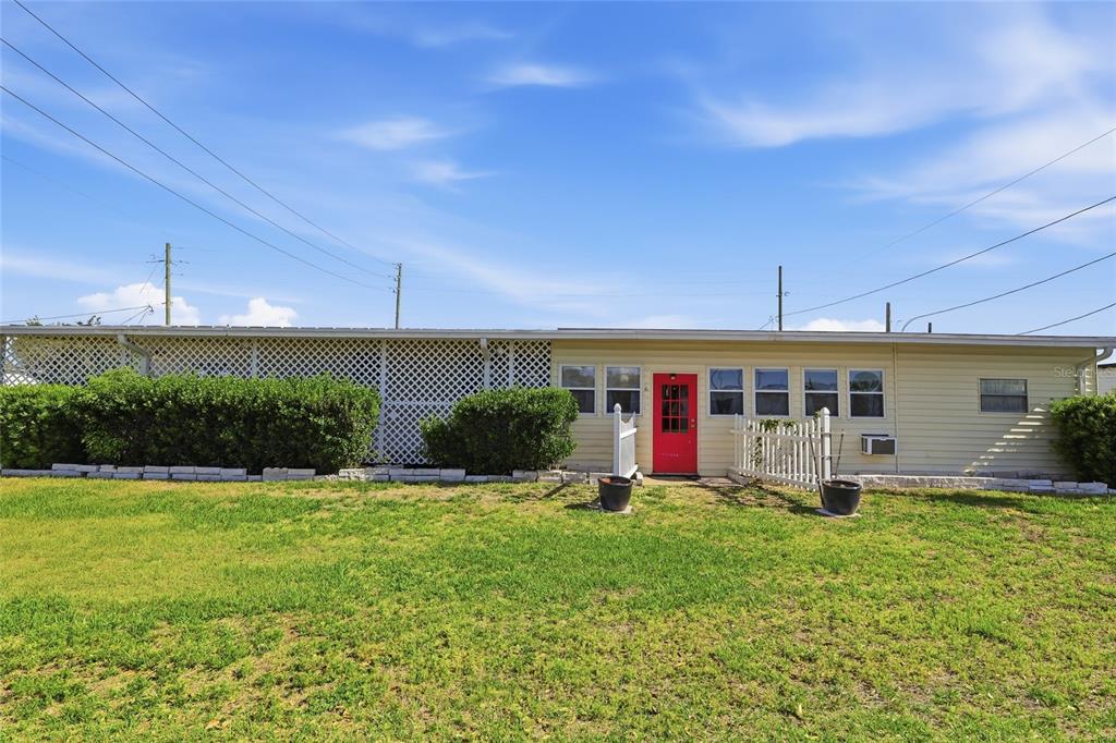 A single-story house with light siding, a red front door, and a lattice-covered porch area — 5246 AMANDA STREET, ZEPHYRHILLS, FL
