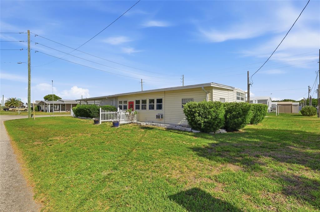 A single-story mobile home with light siding sits on a grassy lot under a blue sky — 5246 AMANDA STREET, ZEPHYRHILLS, FL