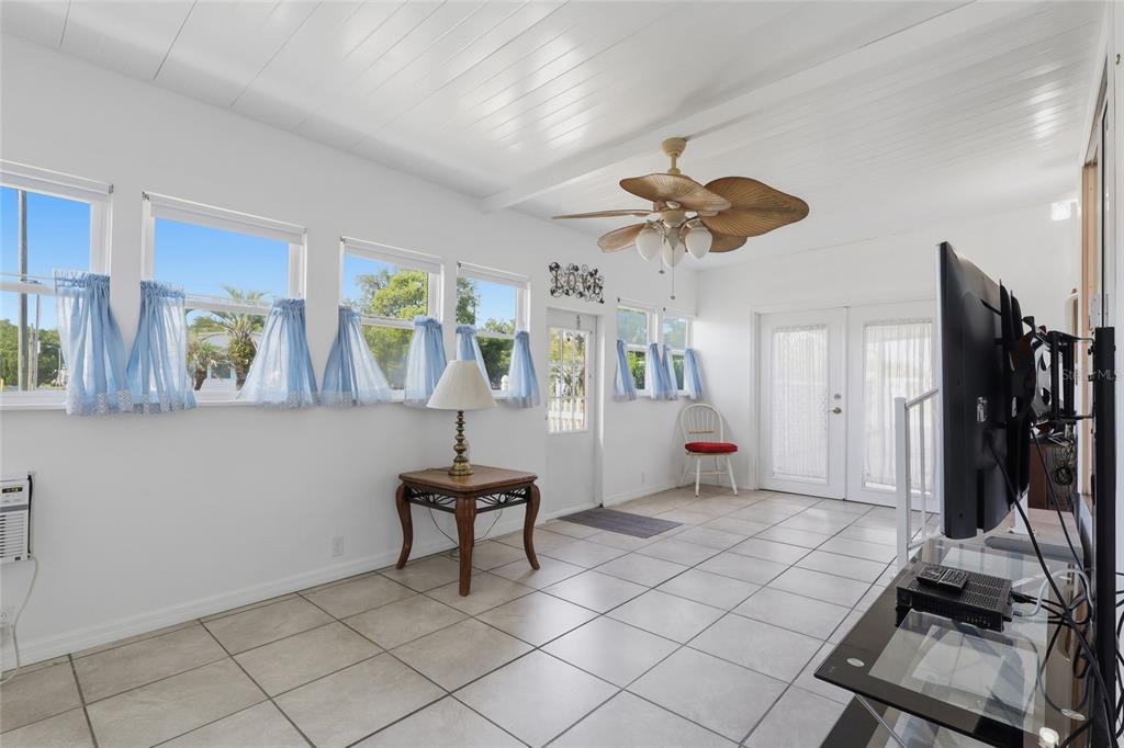 A sunroom with white walls, tile flooring, a ceiling fan, and multiple windows with curtains — 5246 AMANDA STREET, ZEPHYRHILLS, FL