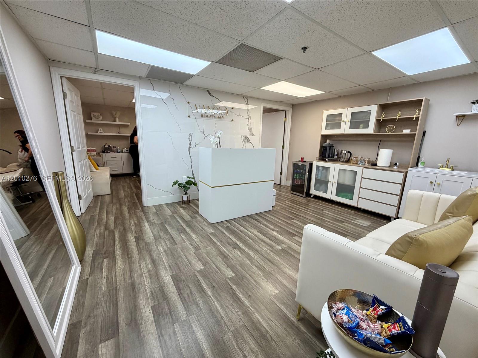 A reception area features a white desk, marble-look wall, wood-look flooring, and a seating area — 7500 NW 25th St # 245, Miami FL 33122, MIAMI, FL