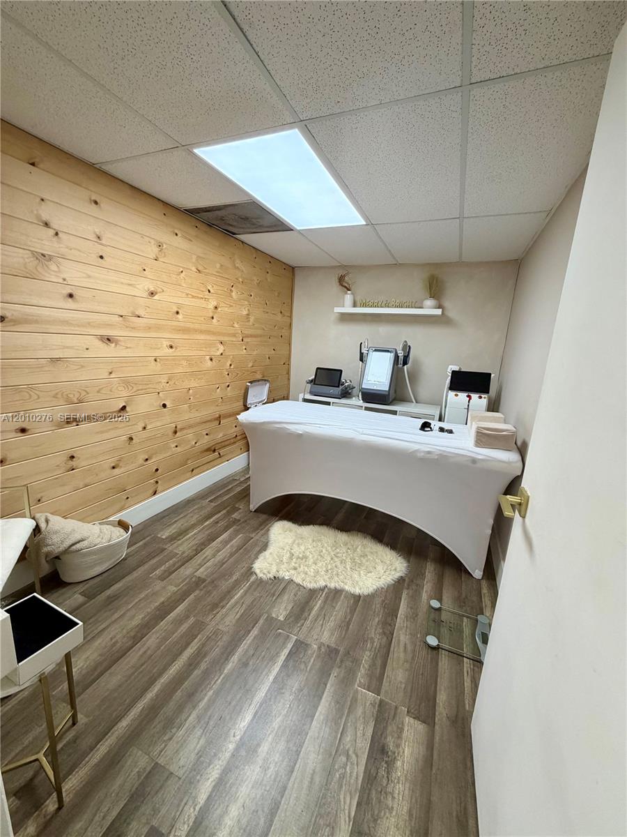 A treatment room features wood-paneled walls, wood-look flooring, and a massage table with medical equipment — 7500 NW 25th St # 245, Miami FL 33122, MIAMI, FL