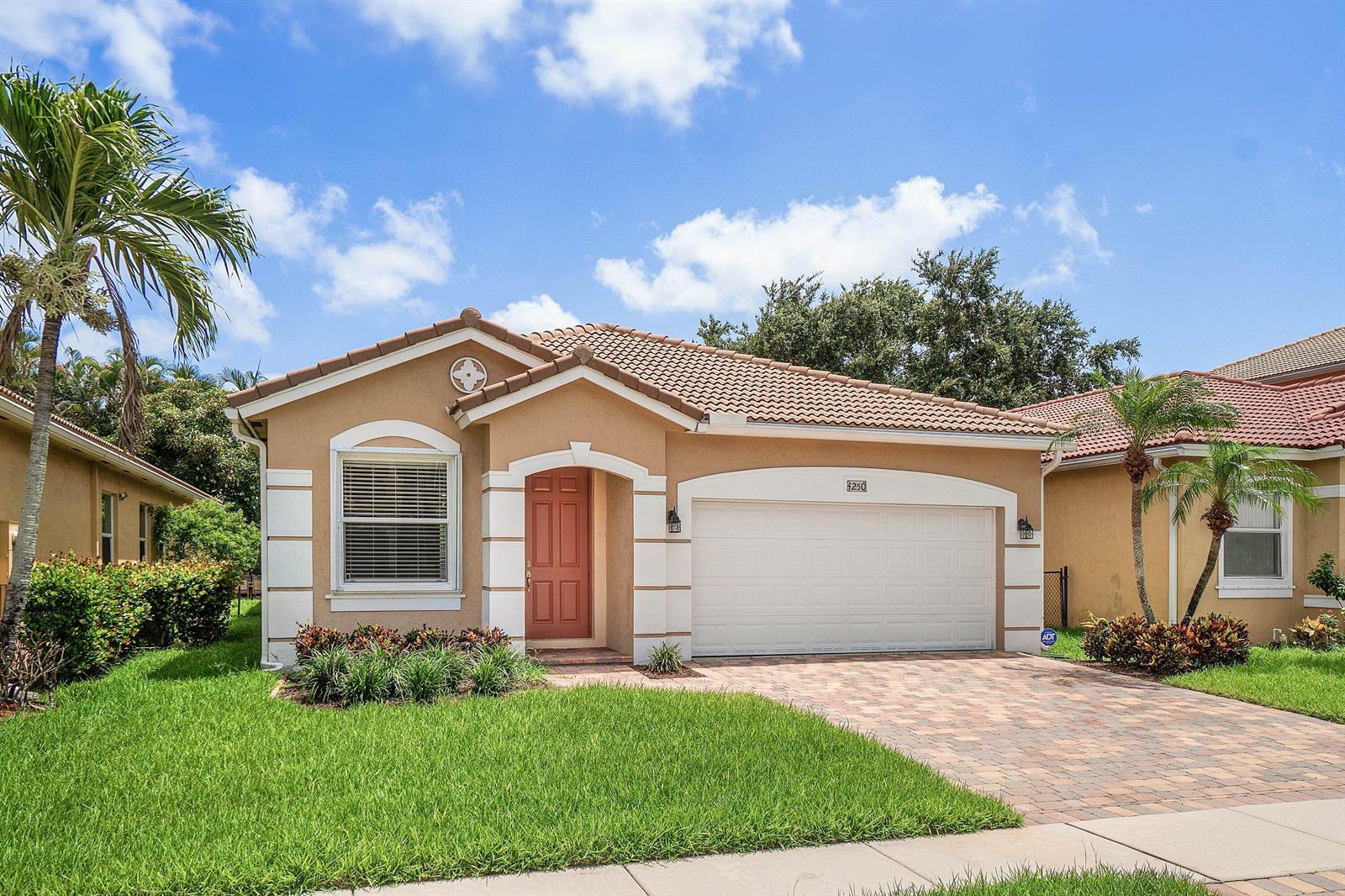 A single-story tan stucco house with a tile roof, a two-car garage, and a driveway — 4250 Key Lime Boulevard, Boynton Beach FL 33436, BOYNTON BEACH, FL