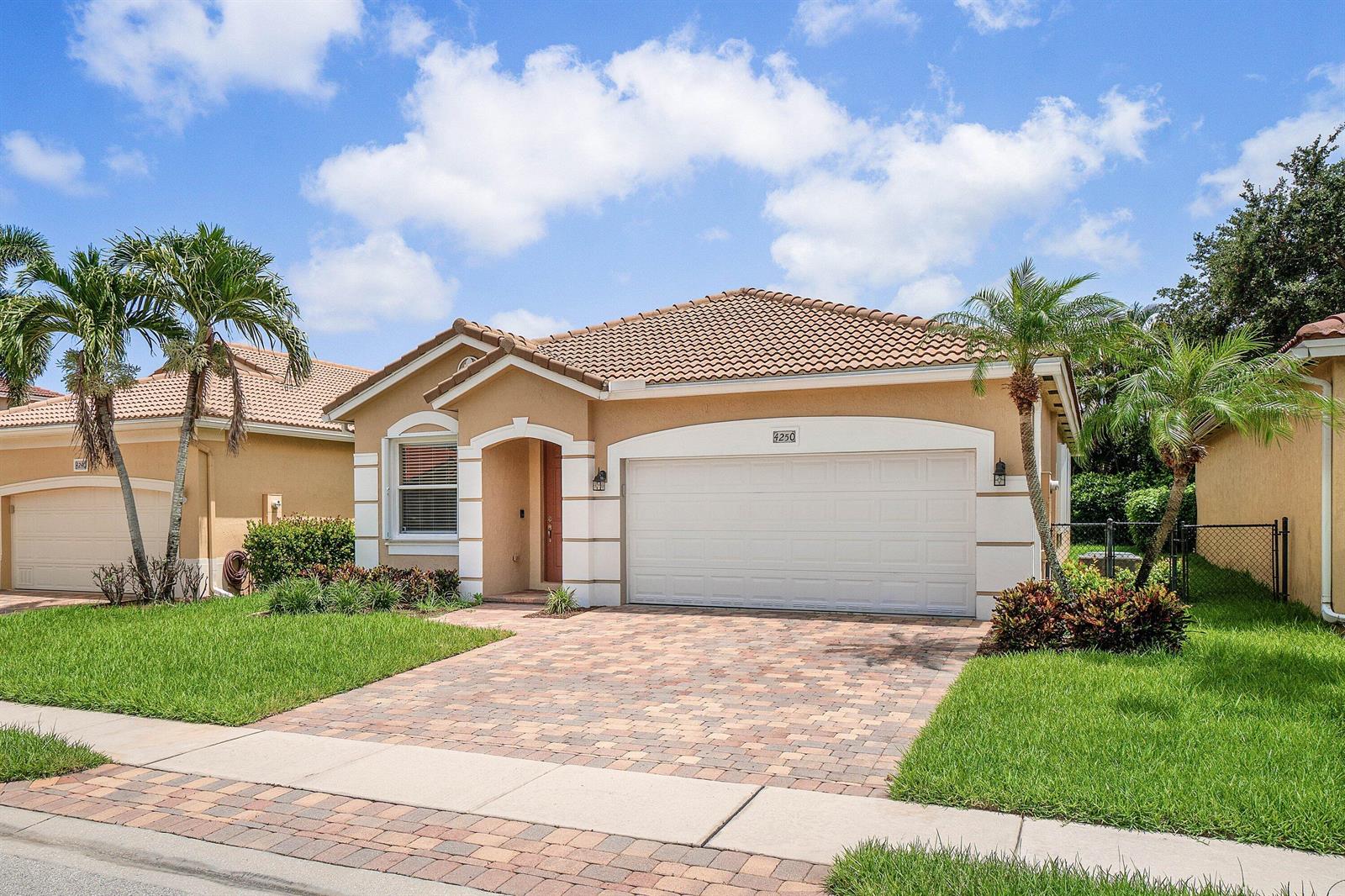 A single-story tan house with a tiled roof, white trim, and a paved driveway — 4250 Key Lime Boulevard, Boynton Beach FL 33436, BOYNTON BEACH, FL