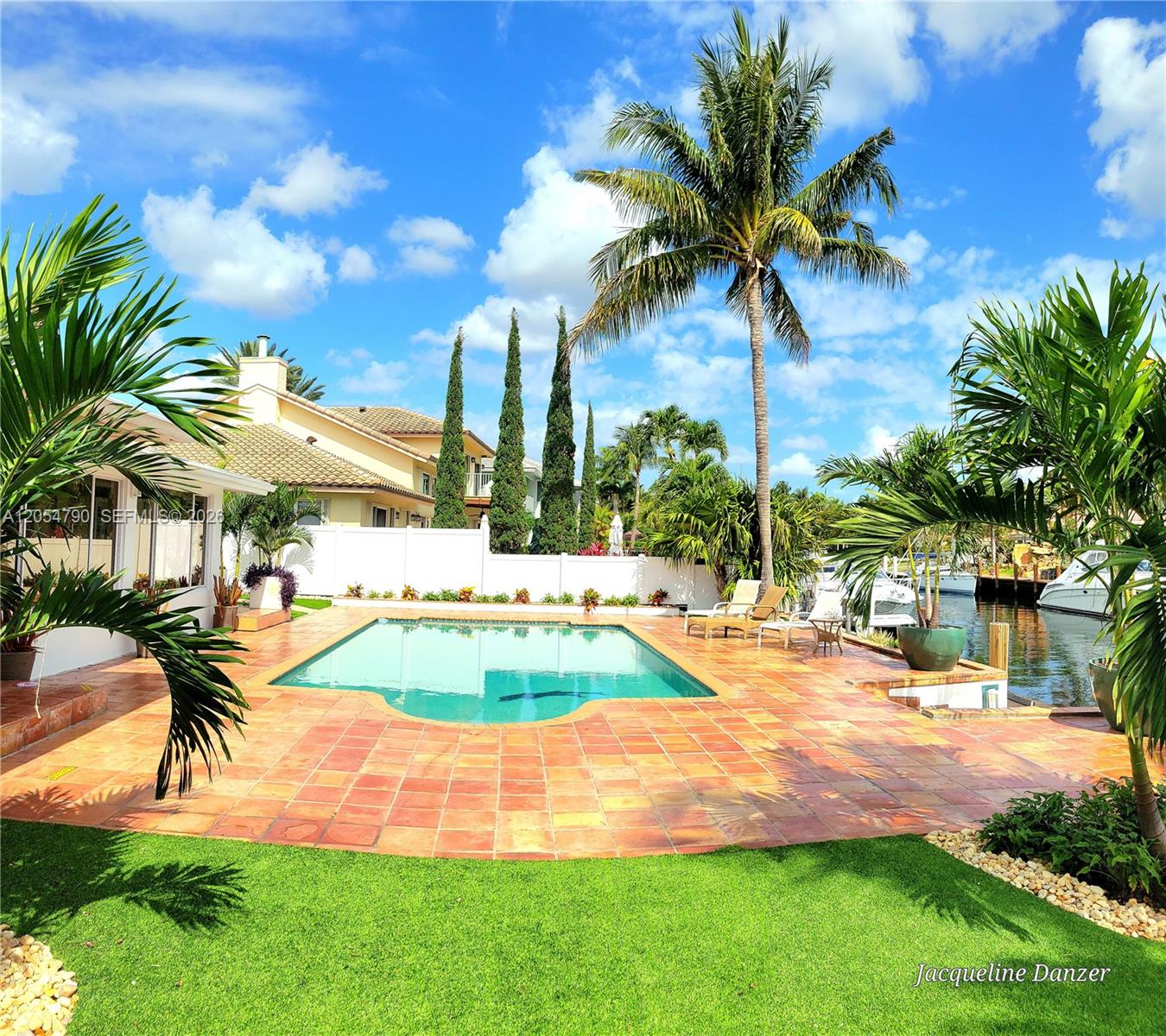 A backyard features a swimming pool, tiled patio, palm trees, and a canal with boats — 2781 NE 23rd Ct # 2781, Pompano Beach FL 33062, POMPANO BEACH, FL