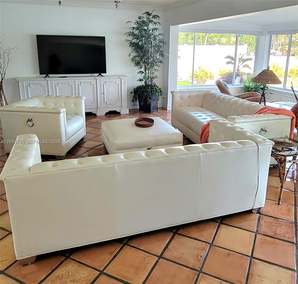 A living room features white tufted leather sofas, a square ottoman, and terracotta tile flooring — 2781 NE 23rd Ct # 2781, Pompano Beach FL 33062, POMPANO BEACH, FL