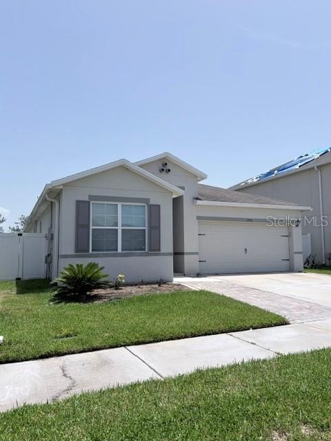 A single-story house with a beige exterior, a two-car garage, and a white privacy fence — 1776 RANGER HIGHLANDS ROAD, KISSIMMEE, FL