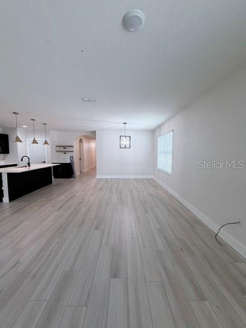 An open-concept room features light wood-look flooring, a kitchen island, and a dining area — 1776 RANGER HIGHLANDS ROAD, KISSIMMEE, FL