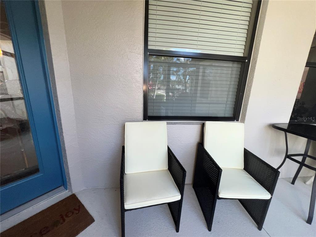 Two black wicker chairs with white cushions sit on a patio near a window — 2522 OSWEGO DRIVE, NORTH PORT, FL