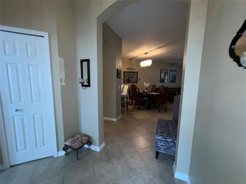 A tiled entryway leads through an arched opening into a dining room with a chandelier — 2522 OSWEGO DRIVE, NORTH PORT, FL