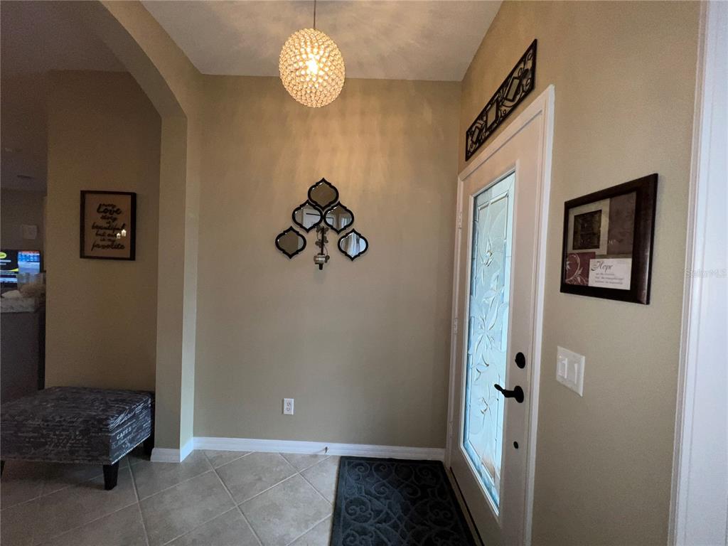 A foyer with tile flooring, a decorative light fixture, a front door, and wall decor — 2522 OSWEGO DRIVE, NORTH PORT, FL