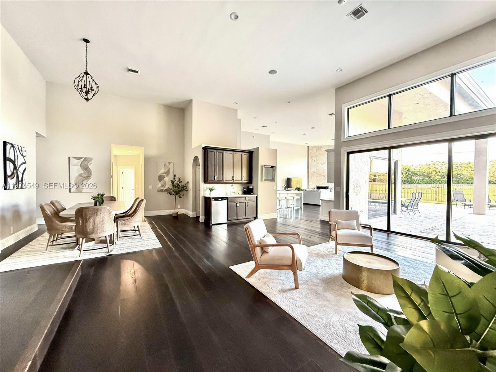 An open-concept living and dining area features dark wood floors, high ceilings, and large windows — 400 Alexandra Cir # 0, Weston FL 33326, WESTON, FL