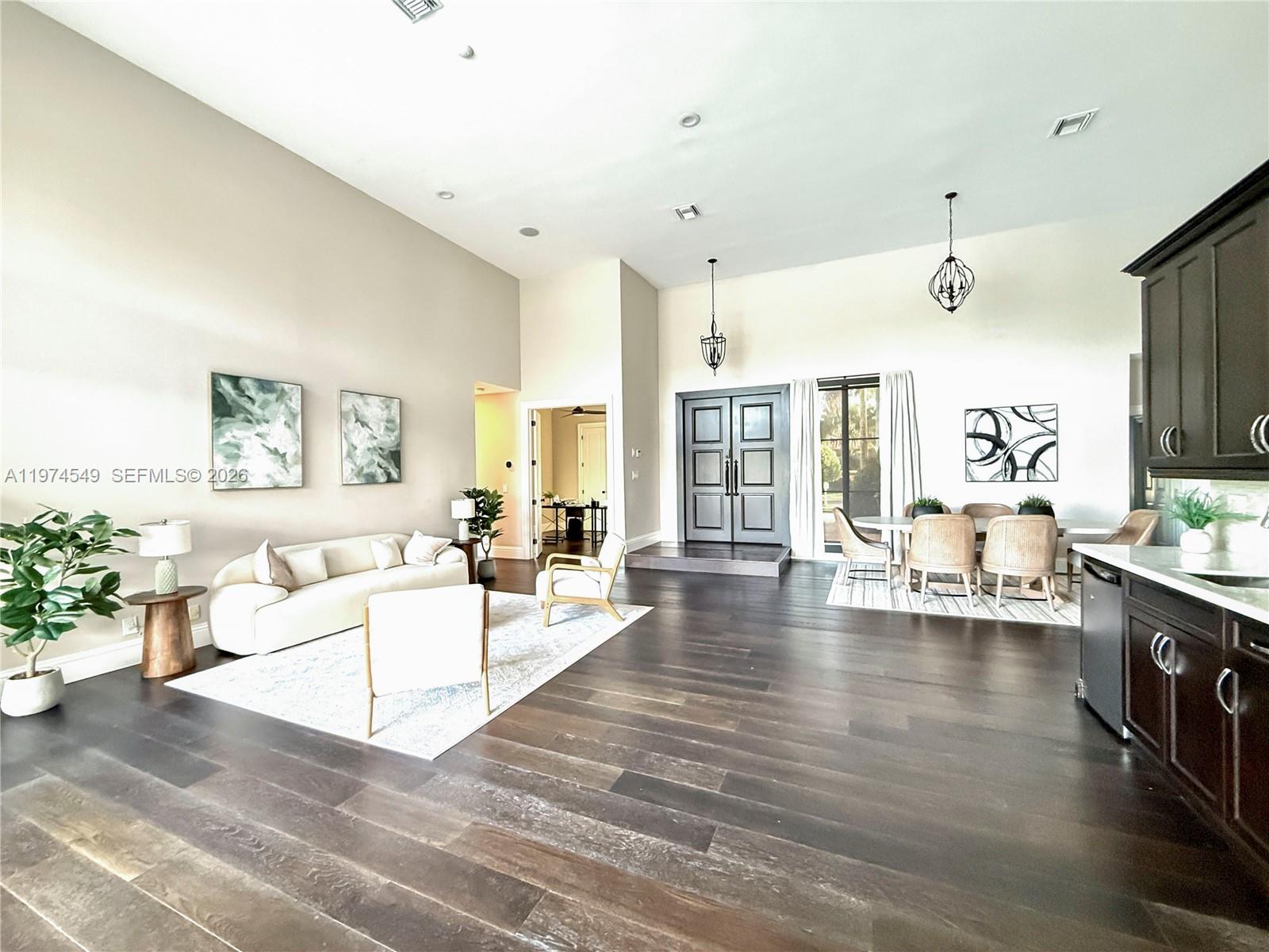 A spacious open-concept living and dining area features dark wood flooring and high ceilings — 400 Alexandra Cir # 0, Weston FL 33326, WESTON, FL